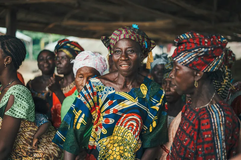 A group of women in colourful wax-print dresses gathered together